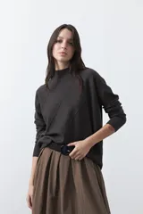 Polera de tejido de punto color gris oscuro, con cuello alto y diseño de rombos en relieve en el frente. Presenta un calce relajado con terminaciones en rib en cuello, puños y ruedo.