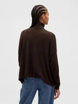 Buzo polera de punto con diseño calado pointelle, de corte holgado, cuello alto y mangas largas con puños acanalados.