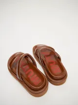 Sandalias de cuero vacuno color marrón con acabado brillante, diseño de dos tiras anchas acolchadas y plataforma baja.