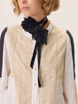 Flor artesanal negra, confeccionada en una mezcla de tejidos con textura, atada a una cinta de terciopelo negro que funciona como choker.