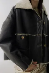 Campera de cuero negro con interior de piel sintética, cuello solapa, cierre frontal con botones y bolsillos delanteros.