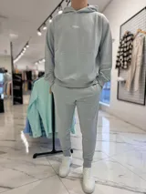 Conjunto de jogging celeste claro compuesto por un canguro con capucha y bolsillo tipo canguro con estampa pequeña del texto "TURK.", y un pantalón de jogging con puños elásticos en los tobillos.