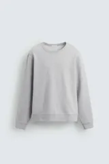 Sudadera de corte regular fit, color gris melange, con cuello redondo, manga larga y acabados en rib. Confeccionada en tejido de algodón con interior afelpado.