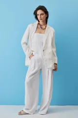 Blazer de lino color blanco, con solapas clásicas, cierre frontal de un botón y bolsillos ribeteados.