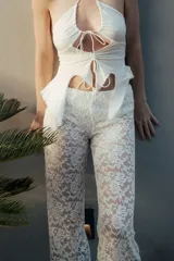 Pantalón largo blanco de encaje con diseño translúcido y corte relajado, que incluye short integrado.
