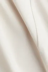 Top de manga larga confeccionado en punto de crepé, con cuello redondo y diseño de peplum. Presenta costuras moldeadoras tanto en el frente como en la espalda.