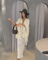 Ruana color crema de tejido grueso con flecos en el borde inferior.