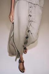 Pantalón ZARA Woman Collection de lino 100%, de tiro medio y color gris claro, con cintura elástica ajustable mediante cordones y bajo redondeado con aberturas laterales.