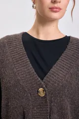 Cardigan de punto en color marrón con escote en V, cierre frontal con botones grandes y mangas largas. Presenta puños y ruedo acanalados.