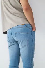 Jean de corte slim fit en color azul claro, con diseño clásico de cinco bolsillos, cierre frontal con botón y cremallera.