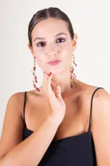 Aros colgantes dorados con detalles de pétalos color borgoña y cuentas de cristal.