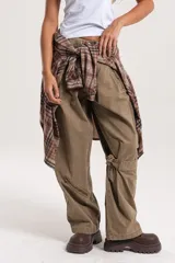 Pantalón cargo de tiro medio-alto en color verde oliva, con diseño holgado, múltiples cierres decorativos y funcionales, y bolsillos laterales.