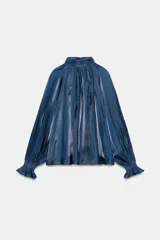 Camisa satinada color azul de cuello alto fruncido y mangas largas con puños elásticos y volados.