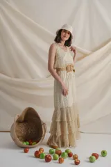 Vestido largo de gasa estampada con flores en tonos de verde y amarillo sobre fondo blanco. Tiene cintura elastizada y terminación en volados.