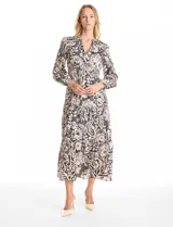 Vestido maxi de satén con estampado floral en tonos negro y beige. Presenta escote en V, hombros fruncidos, mangas largas con puños elásticos y cintura con detalle de punto smock. La falda tiene un diseño escalonado con vuelo.
