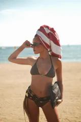 Top de bikini triángulo con estampado geométrico en tonos marrones, amarillos y blancos. Tiene detalle de sol bañado en bronce en el centro.