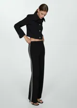 Pantalón de punto fino con diseño acampanado y tiro alto. Presenta una cintura con elástico y detalle de pipping en contraste a lo largo de las piernas.