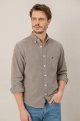 Camisa de pana verde oscuro de corte clásico, con cuello button-down, cierre frontal de botones, bolsillo en el pecho con detalle bordado y mangas largas.