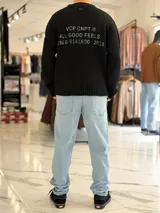 Sweater de punto color marrón, de manga larga, con textura acanalada y texto bordado en la espalda.