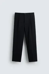 Pantalón negro de corte recto (regular fit) confeccionado en tejido compacto. Presenta pliegues frontales marcados, cierre frontal con botón y cremallera, y bolsillos de vivo en la parte trasera.