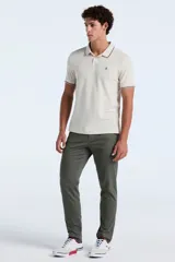 Polo de manga corta confeccionada en tejido piqué con textura tipo waffle, color beige. Presenta cuello clásico con cierre de botones y detalles de líneas en contraste en el borde del cuello y las mangas. Incluye el logo de la marca bordado en el pecho.