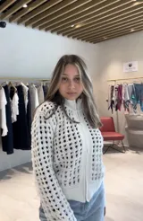 Chaqueta de punto calado color azul marino, con cierre frontal completo, cuello alto y puños tejidos en punto elástico.
