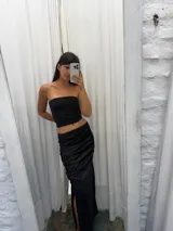 Pollera midi negra de satén con frunces laterales y abertura en la pierna.