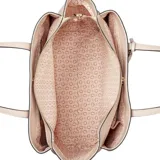 Cartera tipo tote Guess modelo Griffin, color beige, con textura granulada, doble asa de hombro y dije decorativo con forma de flores.