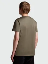 Remera de algodón color verde oliva, con cuello redondo y parche con logo de la marca en el pecho.
