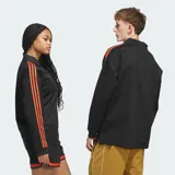 Camisa polo Adidas de manga larga en color negro, con cuello clásico y las icónicas tres tiras naranjas en las mangas. Presenta el logotipo del trébol bordado en naranja en el pecho con la inscripción 'Basketball'.