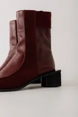 Bota corta de cuero color bordó, con punta cuadrada y taco bloque bajo. Cierre lateral con cremallera.