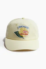 Gorra en sarga de algodón color amarillo claro con diseño bordado en el frente de un limón con hoja y la inscripción "Limonata Sorrento Italia".
