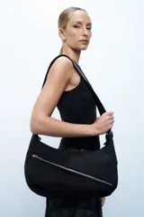 Bandolera de textura tipo gamuza en color negro, con diseño de bolsillo frontal con cierre diagonal y correa regulable.