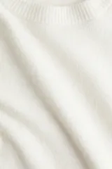 Buzo de punto fino suave con cuello redondo y manga corta. Presenta terminaciones acanaladas en el cuello, puños y bajo.