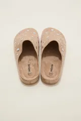 Suecos tipo zueco color negro con acabado de gamuza, decorados con tachas metálicas plateadas circulares. Poseen suela plana y diseño abierto en el talón.