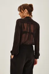 Camisa de transparencia con diseño a rayas verticales, cuello con lazo integrado y mangas largas abullonadas con puños ajustados.