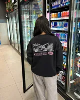 Buzo negro de cuello redondo y manga larga, de corte regular fit. En la espalda presenta un estampado gráfico en color blanco y rosa con la leyenda "Fletes" y el dibujo de una grúa transportando una planta.