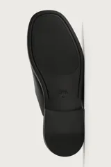 Zueco de vestir para hombre confeccionado en piel de color negro, con horma redonda, diseño destalonado y suela plana a tono.
