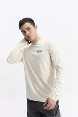 Remera de manga larga color crema, con escote redondo y logo "Mistral since 1976" estampado en el pecho. Tiene un fit regular.