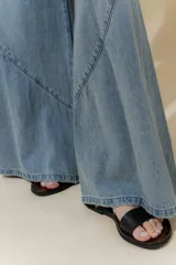 Pantalón de jean color beige, de tiro medio, corte amplio y ruedo acampanado.