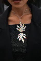 Collar con cadena de acero quirúrgico y dije doble en forma de hojas orgánicas, intervenido con cristales hotfix de colores. El dije es de alpaca plateada.