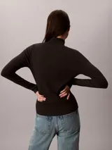 Top negro de manga larga con cuello tortuga, confeccionado en punto fino elástico de algodón BCI y lycra. Presenta un diseño ajustado de corte slim fit con un pequeño parche con el monograma de la marca en el centro del pecho.