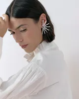 Caravanas tipo ear cuff con diseño de medio sol, compuestas por varillas metálicas plateadas, centro con strass y detalle de resina. Diseño liviano y brillante.