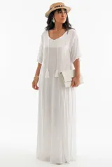 Vestido largo color blanco de corte amplio y fluido, con mangas cortas, escote en V con cordones decorativos con borlas, y delicados detalles bordados tono sobre tono en el pecho y a lo largo de la falda.