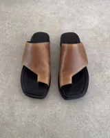 Sandalias negras de cuero vacuno con tira ancha sobre el empeine y espacio para el dedo gordo.