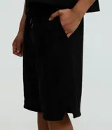 Bermuda baggy de algodón color negro, con cintura elástica con cordón de ajuste, bolsillos y detalles de recortes.