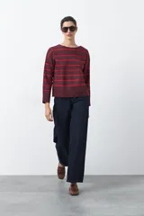 Sweater de tejido de punto con diseño de rayas horizontales en tonos bordó y rojo. Presenta cuello redondo, mangas largas con hombros caídos y terminaciones acanaladas en puños, cuello y ruedo.