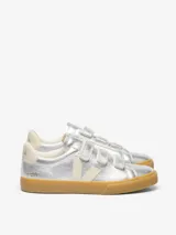 Zapatillas Veja modelo Recife, color plateado metalizado con cierre de tres tiras de velcro. Presentan el logo de la marca en color crema en el lateral y suela de goma color caramelo.