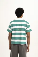 Remera de manga corta color verde oscuro, estilo polo con cuello y abertura frontal. Presenta un bordado central con el texto "PulauCrew" y un laurel en la parte superior.