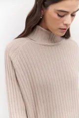 Polera de tejido de punto acanalado en color negro, con cuello alto y diseño de corte recto con largo asimétrico, más corto adelante y más largo atrás.